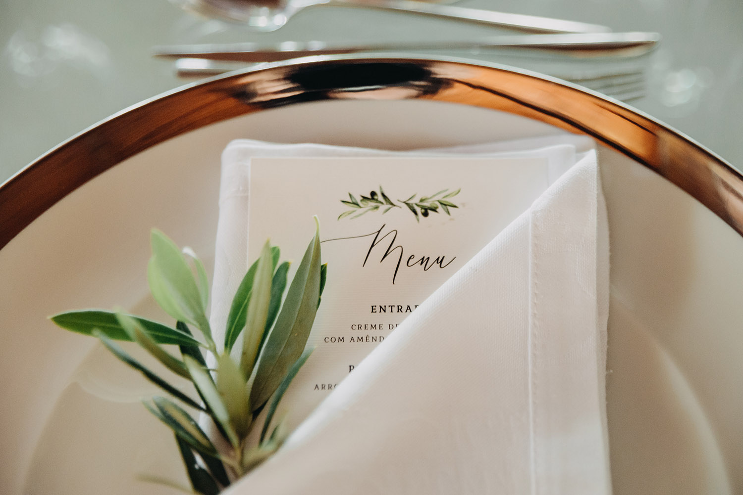 menu weselne lezące na talerzu z gałązką oliwną